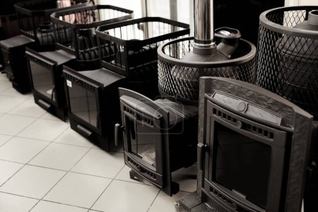 Foto de Chimeneas negras con fuego en casa. Nuevas estufas de carbón en el escaparate. Calefacción en el concepto de casa - Imagen libre de derechos