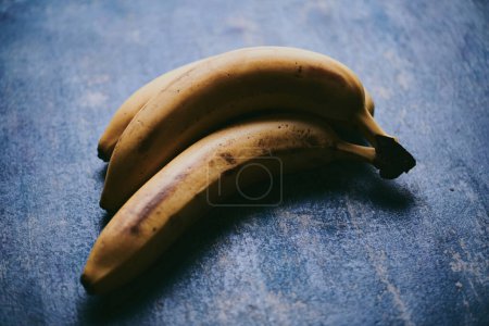 Téléchargez les photos : Gros plan de bananes sur fond bleu texturé - en image libre de droit