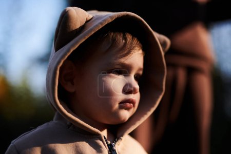 Photo for Close-up portrait of child boy in hooded bear plush jumpsuit. Baby playing outside - Royalty Free Image