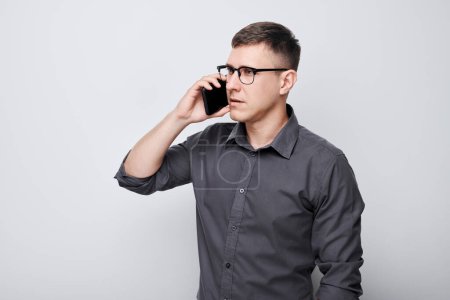 Téléchargez les photos : Portrait de jeune homme d'affaires parlant sur téléphone portable. Personne avec smartphone isolé sur fond blanc - en image libre de droit
