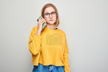 Foto de Retrato de una joven rubia hablando por teléfono móvil con cara feliz y sonriente. Persona con teléfono inteligente aislado en el fondo blanco - Imagen libre de derechos