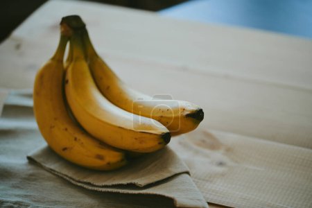 Foto de Primer plano de un ramo de plátanos sobre un fondo de mesa de cocina de madera - Imagen libre de derechos