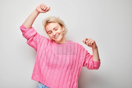 Photo for Portrait of smiling face blond young woman clenching fists and rejoicing, celebrating victory isolated on white studio background, advertising banne - Royalty Free Image