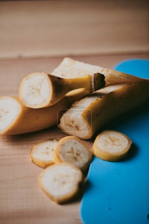 Photo for Close-up of peeled sliced banana on wooden table background - Royalty Free Image
