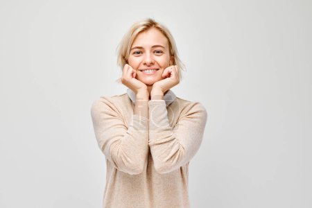 Téléchargez les photos : Portrait jeune femme blonde souriante joyeux toucher heureux choqué visage isolé sur fond de studio blanc, banne publicitaire - en image libre de droit