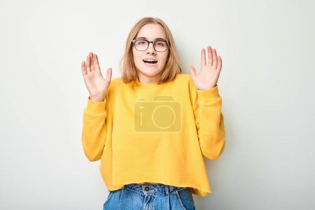 Porträt Studentenmädchen glücklich lächelnd fröhlich mit erhobenen Handflächen und schockiertem offenen Mund isoliert auf weißem Studiohintergrund