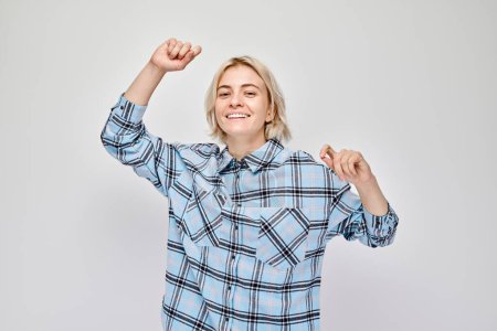 Foto de Retrato de cara sonriente joven rubia apretando puños y regocijándose, celebrando la victoria aislada en el fondo del estudio blanco, publicidad banne - Imagen libre de derechos