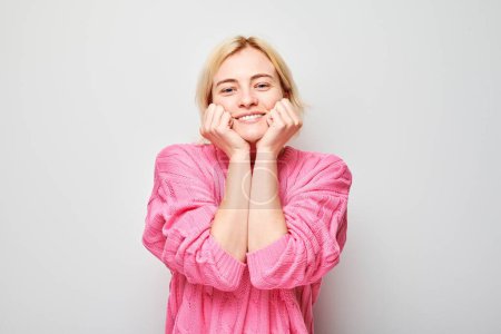 Foto de Retrato mujer joven rubia sonriendo alegremente tocando la cara conmocionada feliz aislado en fondo de estudio blanco, banne publicidad - Imagen libre de derechos