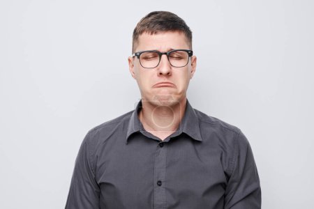 Foto de Retrato de un tipo con cara triste ofendido y llorando sobre fondo blanco. Nervios, estrés, incertidumbre concep - Imagen libre de derechos