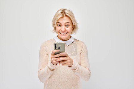 Photo for Portrait of young blond woman holding mobile phone in hand with happy smiling face. Person with smartphone isolated on white backgroun - Royalty Free Image