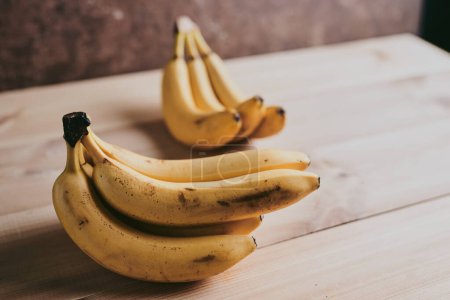 Photo for Close-up of a bunch of bananas on a wooden kitchen table background - Royalty Free Image