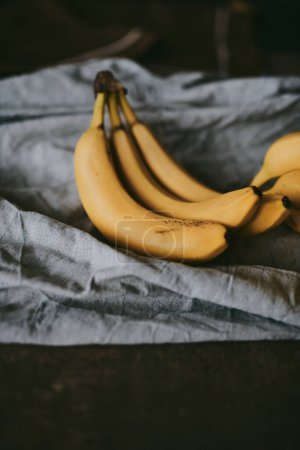 Photo for Close-up of a bunch of bananas on a dark fabric background - Royalty Free Image