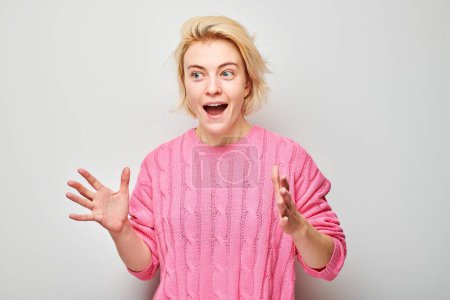 Foto de Retrato rubia joven feliz cara sonriendo alegremente con las palmas levantadas y la boca abierta conmocionada aislado en fondo de estudio blanco - Imagen libre de derechos