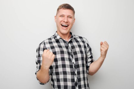 Photo for Portrait of smiling face man clenching fists and rejoicing, celebrating victory isolated on white studio background, advertising banne - Royalty Free Image