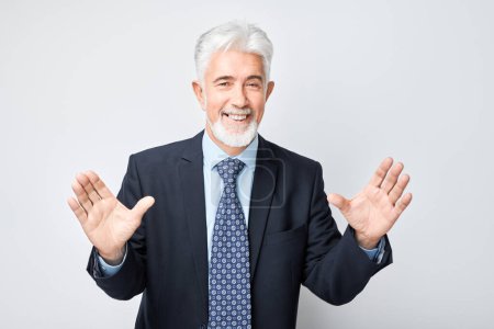 Foto de Retrato hombre de pelo gris cara feliz sonriendo alegremente con las palmas levantadas y la boca abierta conmocionado aislado en fondo de estudio blanco - Imagen libre de derechos