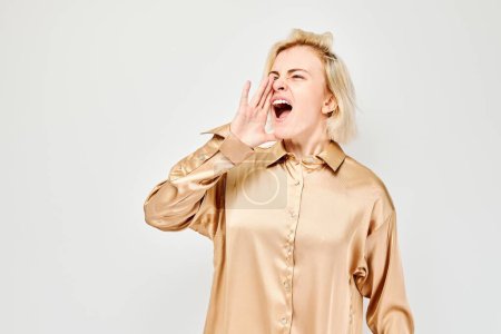 Porträt eines blonden Mädchens, das laut schreit, mit Händen, Nachrichten, Handflächen gefaltet wie ein Megafon, isoliert auf weißem Hintergrund