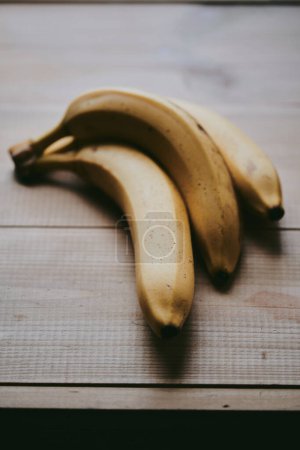 Photo for Close-up of a bunch of bananas on a wooden kitchen table background - Royalty Free Image