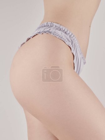 Schlank gebräunter Frauenkörper isoliert auf weißem Hintergrund. Nahaufnahme eines Mädchens in lila Unterwäsche