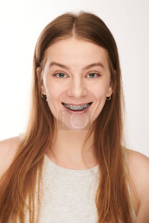 Photo for A young woman with braces smiles and looks toothily at the camera. Orthodontic dental treatment - Royalty Free Image