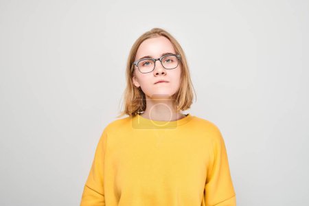 Foto de Retrato de chica en casual amarillo y gafas con expresión neutra - Imagen libre de derechos
