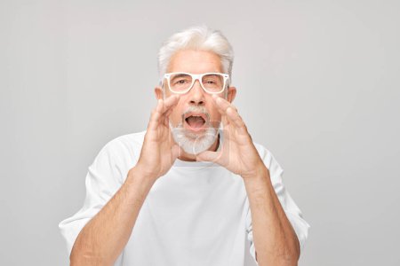 Photo for Portrait of senior man in white shouting loudly with hands, news, palms folded like megaphone isolated on white background - Royalty Free Image