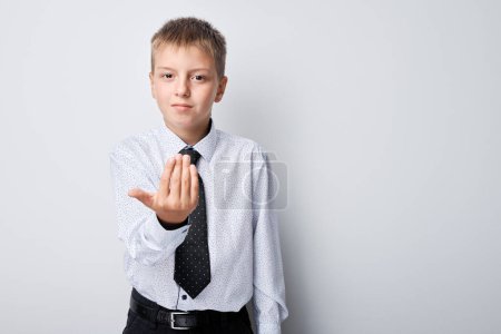 Téléchargez les photos : Portrait de garçon en uniforme scolaire étendant la main pour une poignée de main et une offre de coopération - en image libre de droit