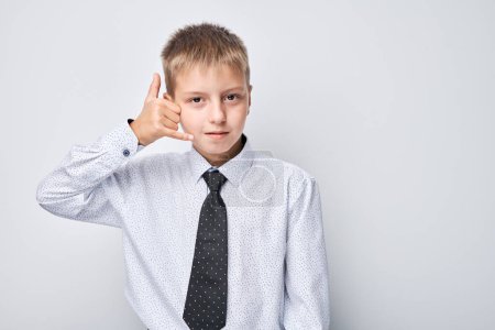 Foto de Niño en camisa y corbata gesto llámame signo, aislado sobre fondo gris. - Imagen libre de derechos