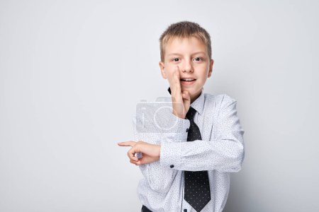 Foto de Retrato niño en uniforme escolar señalando con el dedo en el espacio vacío para la publicidad de productos o texto - Imagen libre de derechos