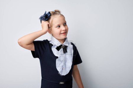 Téléchargez les photos : Fille souriante posant avec accessoire de cheveux de fleur bleue sur un fond gris clair. - en image libre de droit