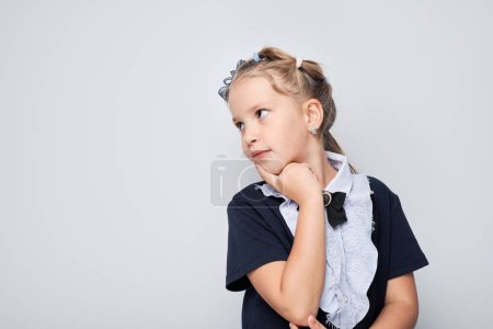 Photo for Thoughtful young girl with hand on chin looking away, isolated on a grey background. - Royalty Free Image
