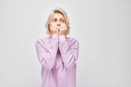 Photo for Portrait girl with sad face worried, biting nails on white background. Nerves, stress, uncertainty - Royalty Free Image