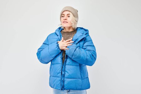 Woman in winter attire feeling cold, isolated on a light background.