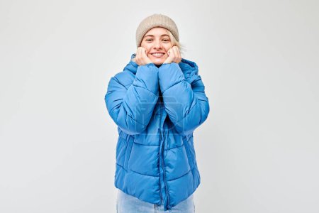 Téléchargez les photos : Jeune femme en tenue d'hiver avec la main sur la joue sur un fond blanc. - en image libre de droit