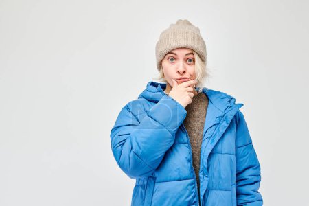 Photo for Woman in winter attire looking thoughtful against a light background. - Royalty Free Image