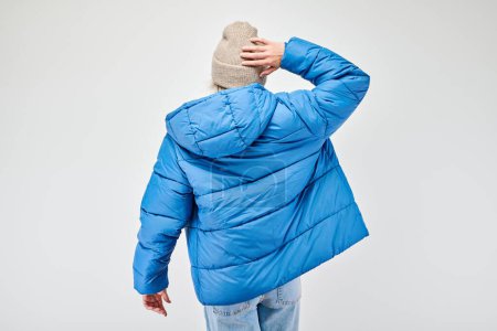 Foto de Persona en chaqueta hinchable azul mirando hacia otro lado, aislada sobre fondo blanco. - Imagen libre de derechos