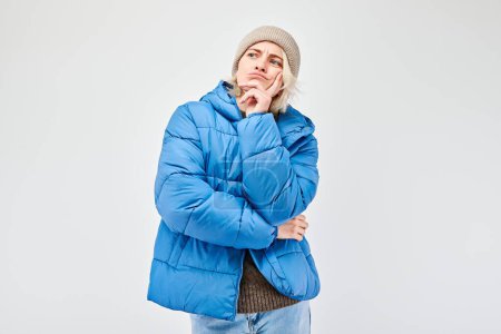 Téléchargez les photos : Femme en tenue d'hiver avec une expression dispendieuse, pense, choisit isolé sur fond clair - en image libre de droit