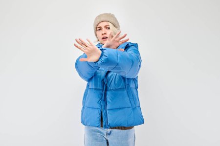 Woman in winter attire gesturing stop with his hands against a white background.