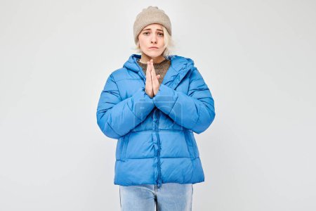 Téléchargez les photos : Femme en tenue d'hiver mains croisées en prière pose d'action de grâces isolée sur fond clair. - en image libre de droit
