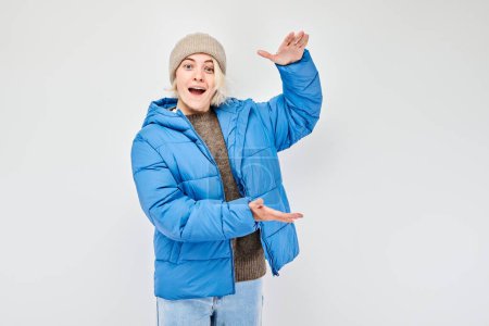 Téléchargez les photos : Personne joyeuse en tenue d'hiver présentant avec des gestes de main sur un fond clair. - en image libre de droit