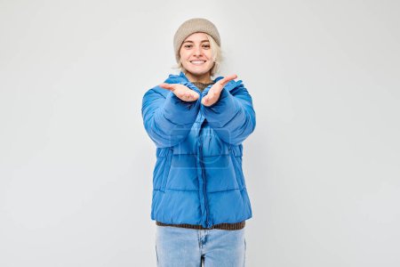 Téléchargez les photos : Femme souriante en vêtements d'hiver gesticulant avec les mains sur un fond gris. - en image libre de droit