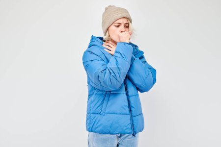 Téléchargez les photos : Jeune femme veste d'hiver bleu froid, soufflant sur les mains, isolé sur fond blanc. - en image libre de droit