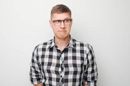 Téléchargez les photos : Portrait de jeune homme sceptique en lunettes et chemise à carreaux, debout sur fond blanc - en image libre de droit