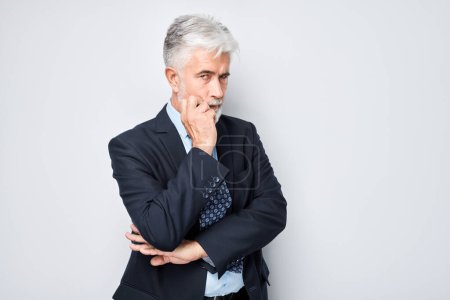 Photo for Portrait of mature businessman with gray hair and beard wearing suit looking thoughtful - Royalty Free Image
