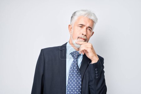 Photo for Thoughtful senior businessman hand on chin, contemplating isolated on a light background. - Royalty Free Image
