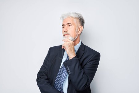 Photo for Thoughtful senior businessman hand on chin, contemplating isolated on a light background. - Royalty Free Image