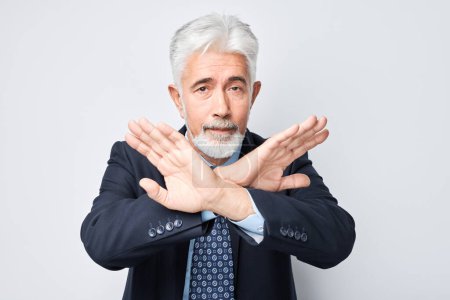 Photo for Senior businessman making stop gesture with arms crossed, signaling denial or restriction - Royalty Free Image