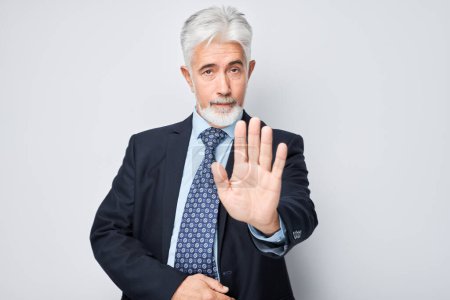 Téléchargez les photos : Homme d'affaires senior faisant un geste d'arrêt avec un bras, signalant un déni ou une restriction - en image libre de droit