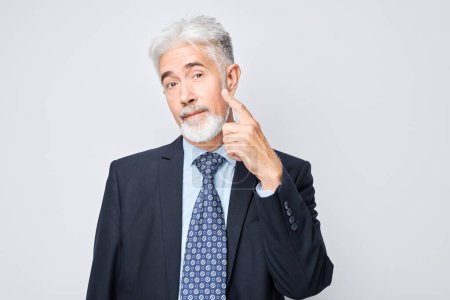 Photo for Mature businessman with gray hair pointing upwards, having an idea, isolated on a light background. - Royalty Free Image
