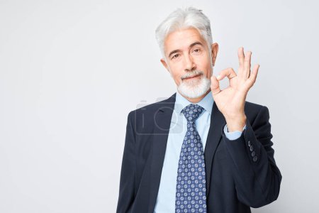 Foto de Hombre de negocios senior haciendo gesto OK con la mano aislada sobre fondo blanco. - Imagen libre de derechos