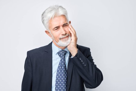 Photo for Senior with grey hair in pain touching cheek, suffering from toothache isolated on grey background. - Royalty Free Image